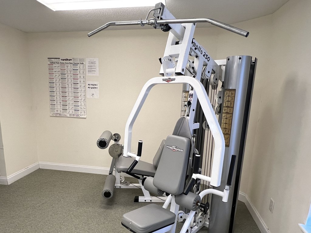 A gym machine is in a room with a chart on the wall.