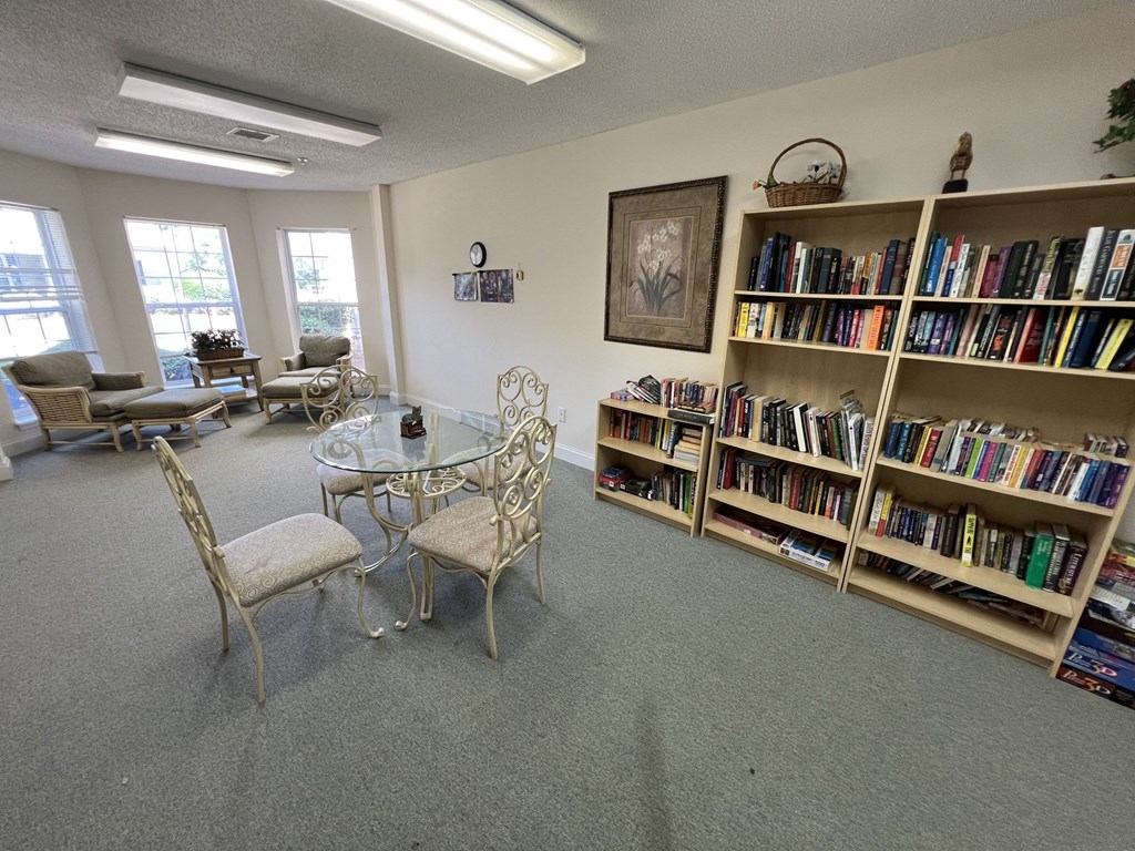 A room with a table, chairs, and a bookshelf filled with books.