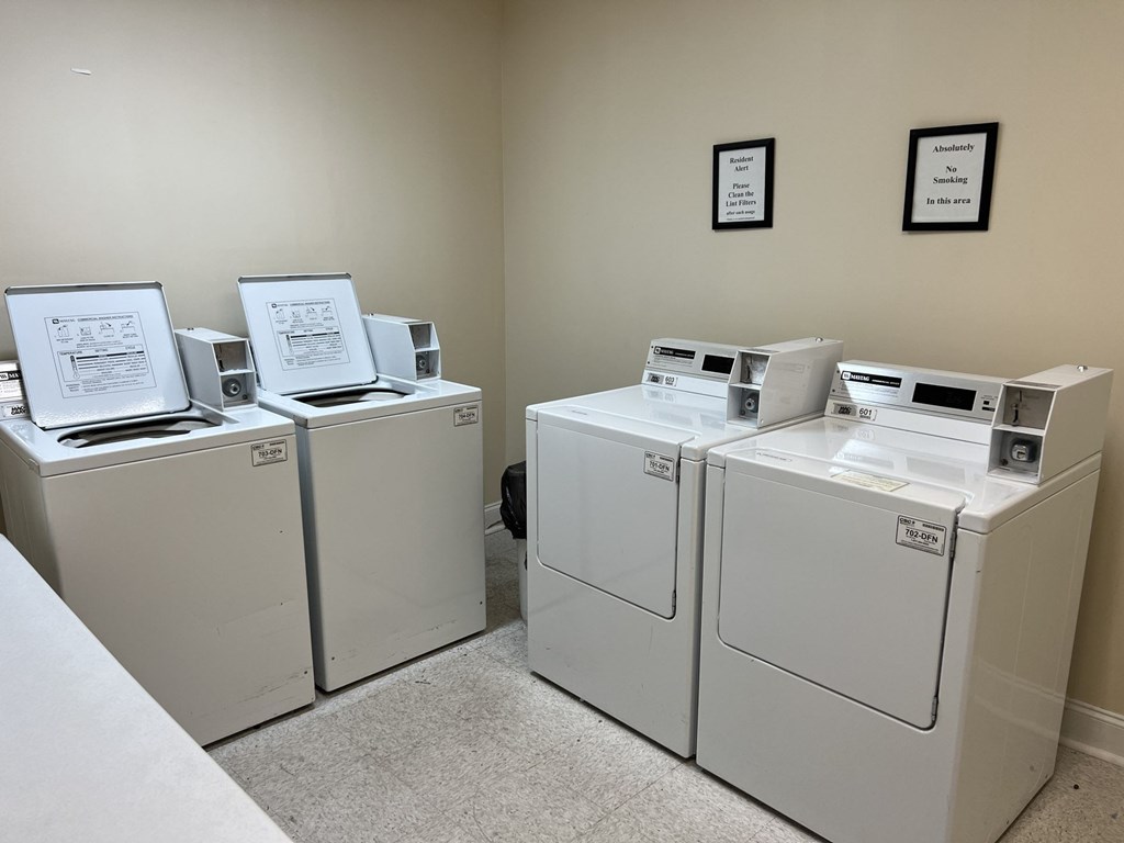 A row of washing machines are lined up in a laundry room.