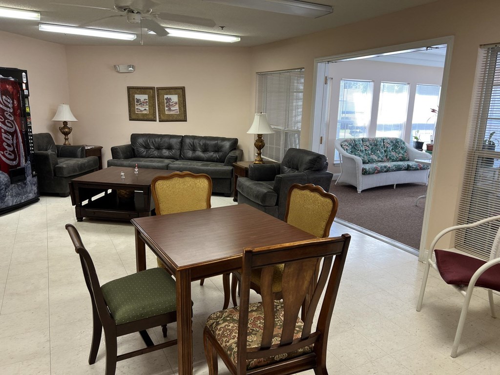 A room with a wooden table and chairs in the foreground and a couch and a cushioned chair in the background.