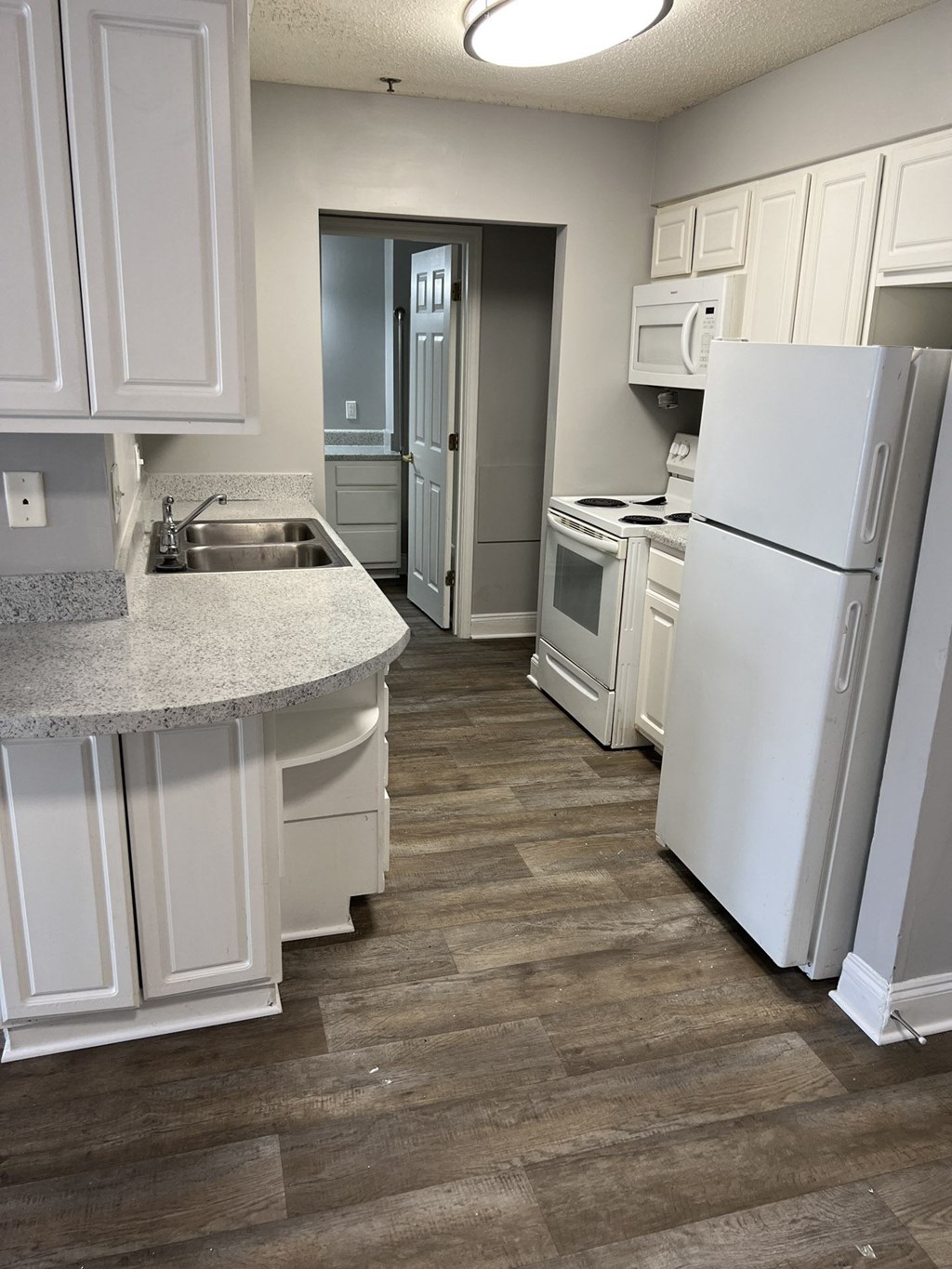 A kitchen with white appliances and cabinets.