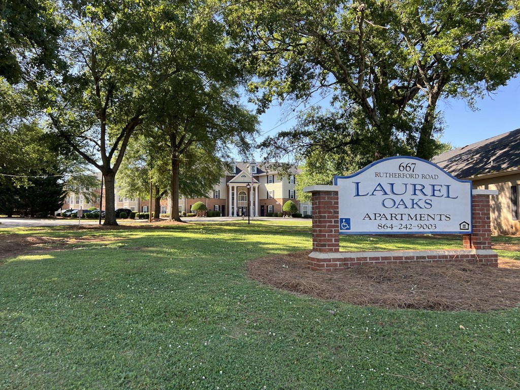 A sign for Laurel Oaks Apartments is in the foreground of a grassy area.