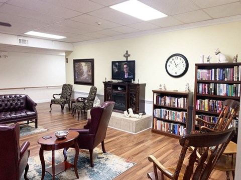 A living room with a fireplace, chairs, and a bookshelf.