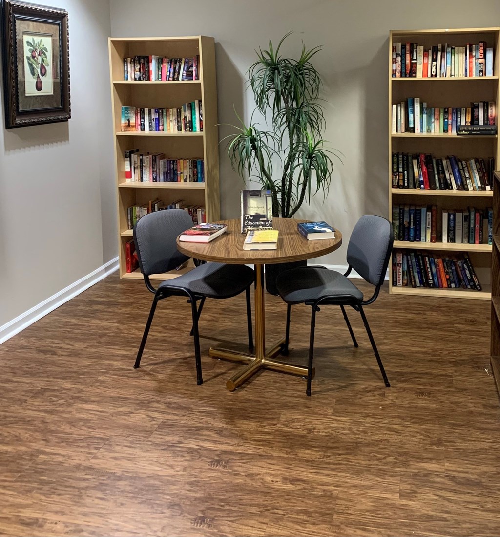 A room with a table, chairs, and bookshelves.