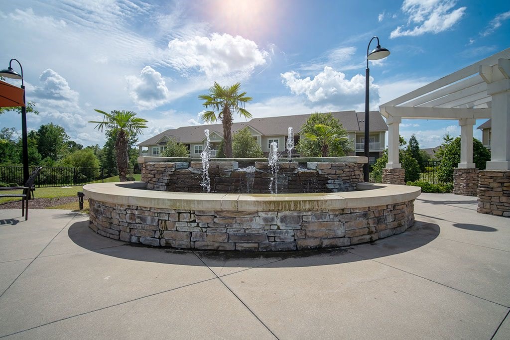 a fountain in the center of a patio with a building in the background