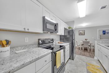 A kitchen with white cabinets and a granite countertop.