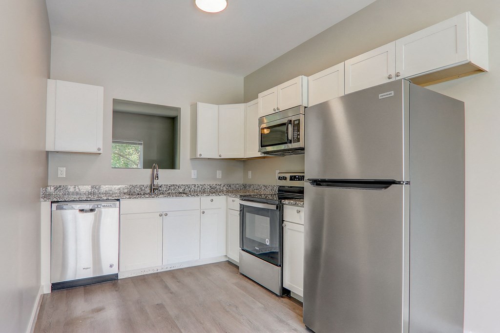 Greenville, SC Townhomes With Attached Garage - Marbella Townhomes - A Kitchen With Stainless Steel Appliances, White Cabinetry, Granite Countertops, A Sleek Faucet, And An Orchid Centerpiece.