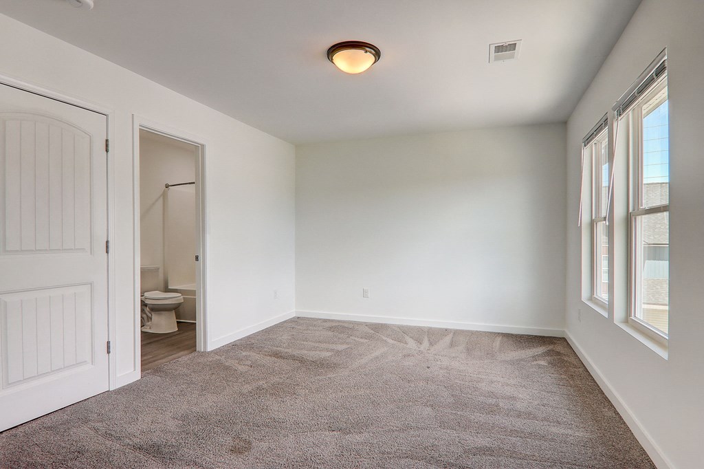 an empty living room with a door to a bathroom