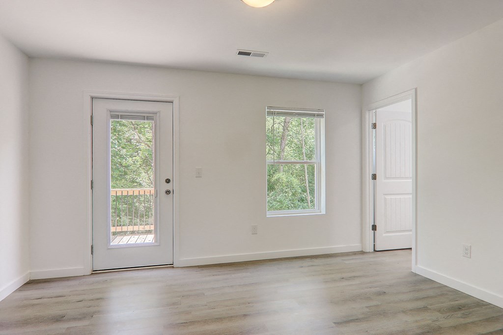 an empty living room with white walls and a door and window
