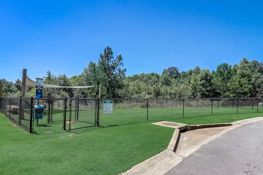 Dog-Friendly Townhomes In Greenville, SC - Marbella Townhomes - A Dog Park With Green Grass, Secure Fencing, Shaded Areas, Clear Signage, And Surrounded By Trees.