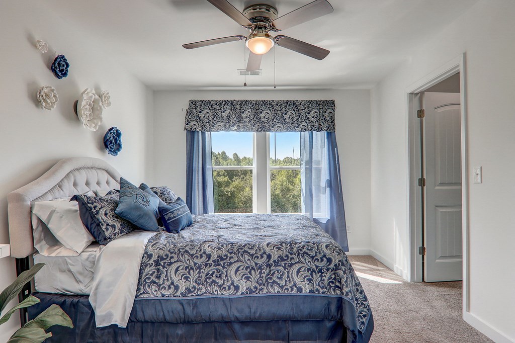 3 Bedroom Townhomes In Greenville, SC - Marbella Townhomes - A Bedroom With A Large Bed, White Comforter, Blue Accents, A Window, And Modern Rustic Charm.
