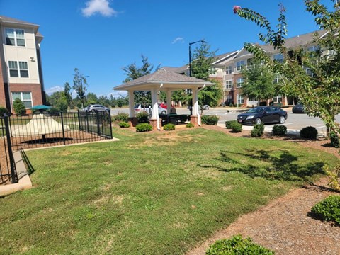 A sunny day at a residential complex with a gazebo and a parking lot.