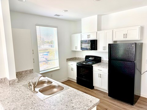a kitchen with a sink and a black refrigerator