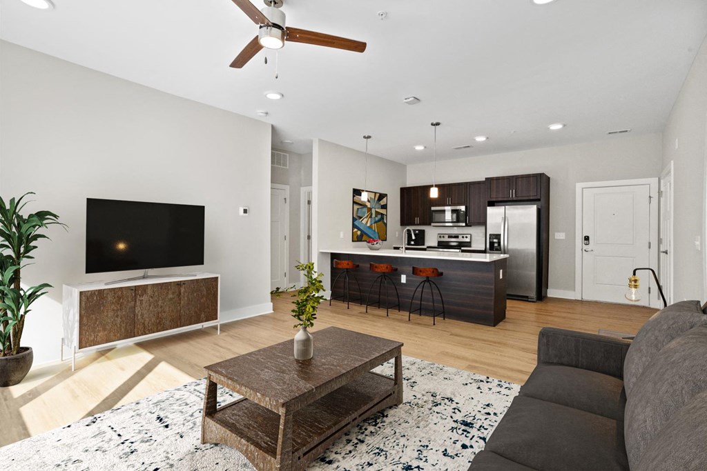 A model unit of Park View Greer Apartments in Greer, SC, featuring a TV, a couch, a coffee table and a kitchen with an island, stools and stainless steel appliances.