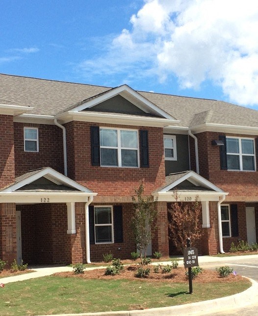 A red brick house with a black sign in front.
