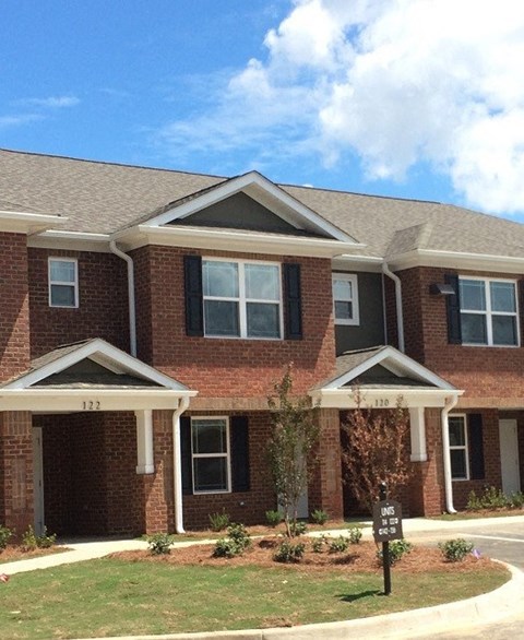 A red brick house with a black sign in front.