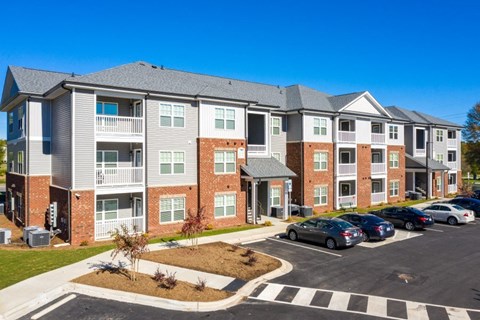 A large apartment complex with a parking lot in front.