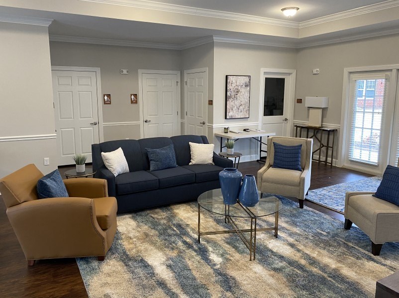 A living room with a black couch and a glass coffee table.