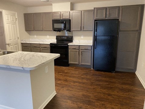A kitchen with a black refrigerator and white countertops.