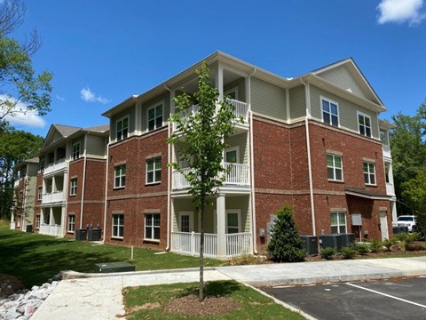 A large brick apartment building with a tree in front.