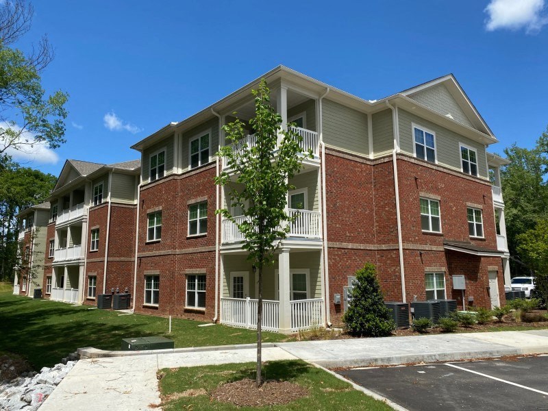 A large brick apartment building with a tree in front.