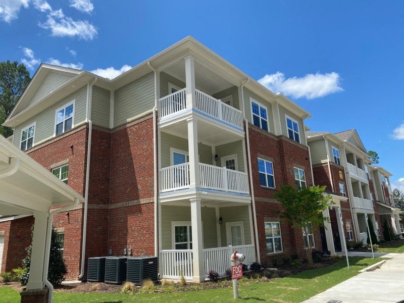 A red brick apartment building with white balconies and a mailbox in front.