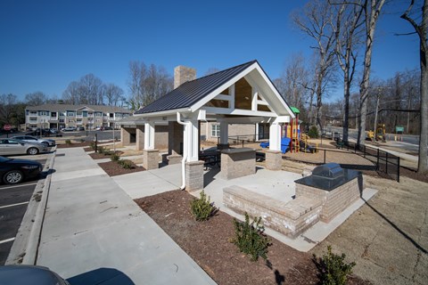 A small building with a black roof is surrounded by a parking lot.