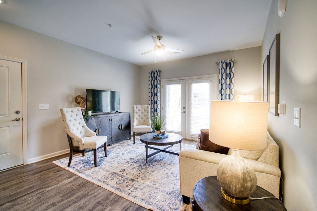 1 Bedroom Apartments in Boiling Springs, SC - Peachtree Village - Living Area with Wood-Style Flooring, Couch, Two Armchairs, Coffee Table, Nightstand, Lamp, Media Cabinet, and TV.