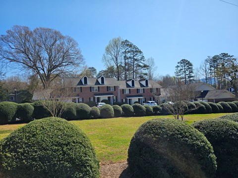 a large brick house with a green lawn and hedges