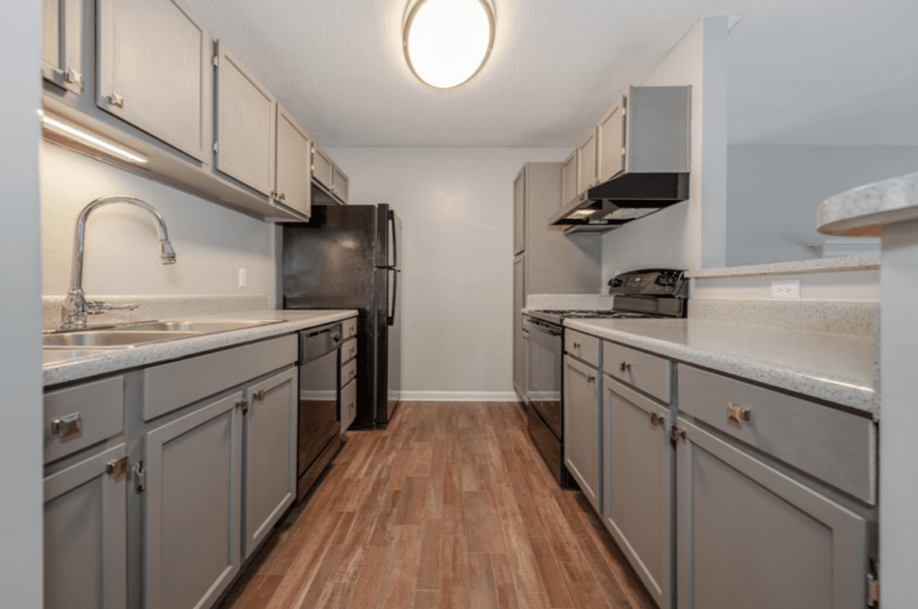 A kitchen with wooden floors and grey cabinets.
