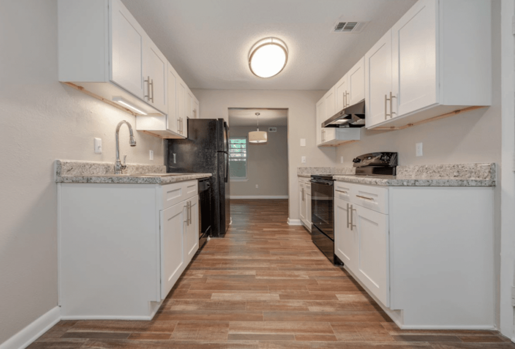 A kitchen with white cabinets and a marble countertop.