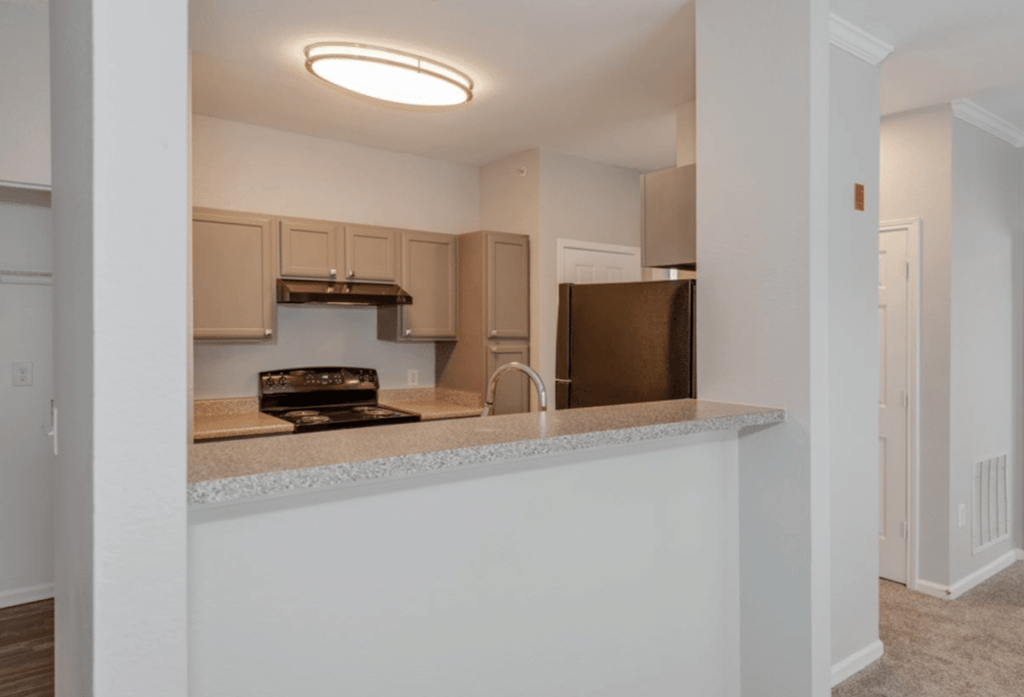 A kitchen with a white counter and brown cabinets.