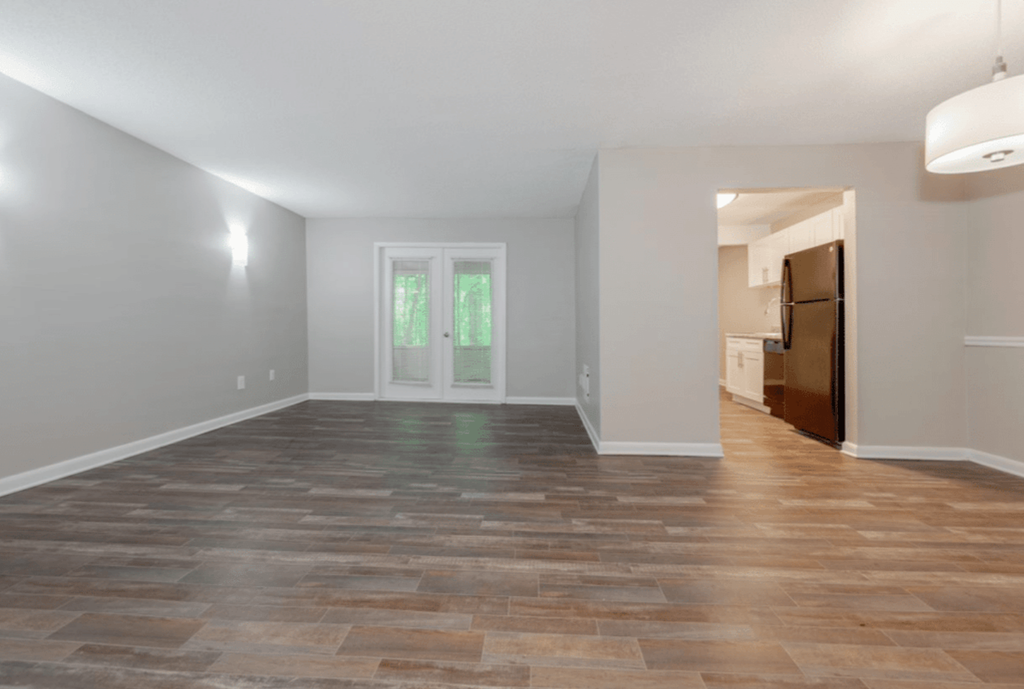 A room with a wooden floor and a door leading to another room.