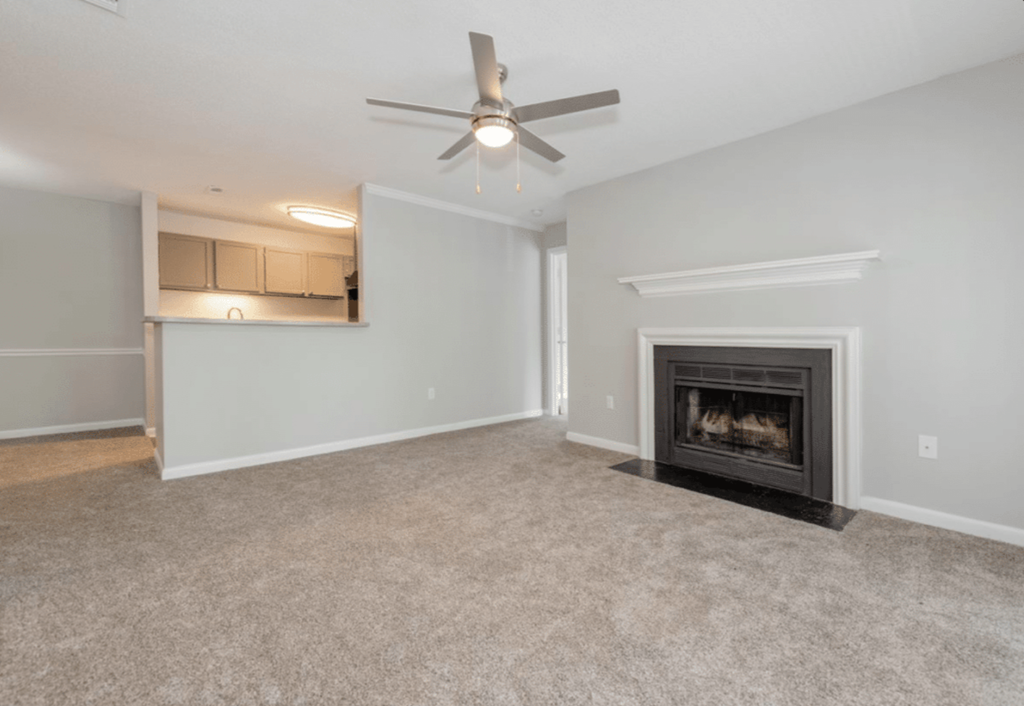A living room with a fireplace and a ceiling fan.