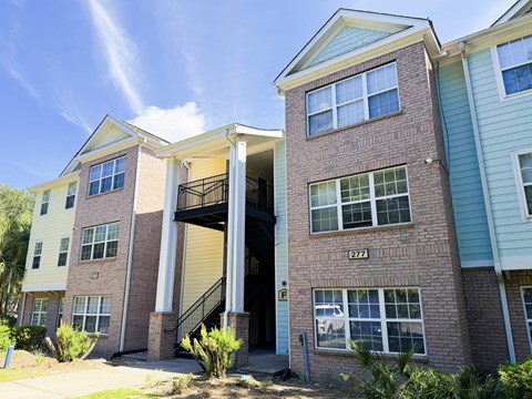 A two-story brick apartment building with a garage door open.