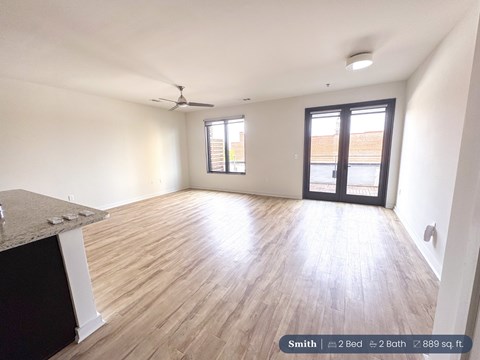 A spacious room with a ceiling fan and a large window.