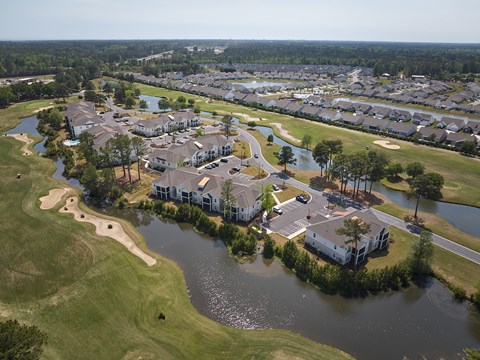 A golf course with a lake and houses in the background.