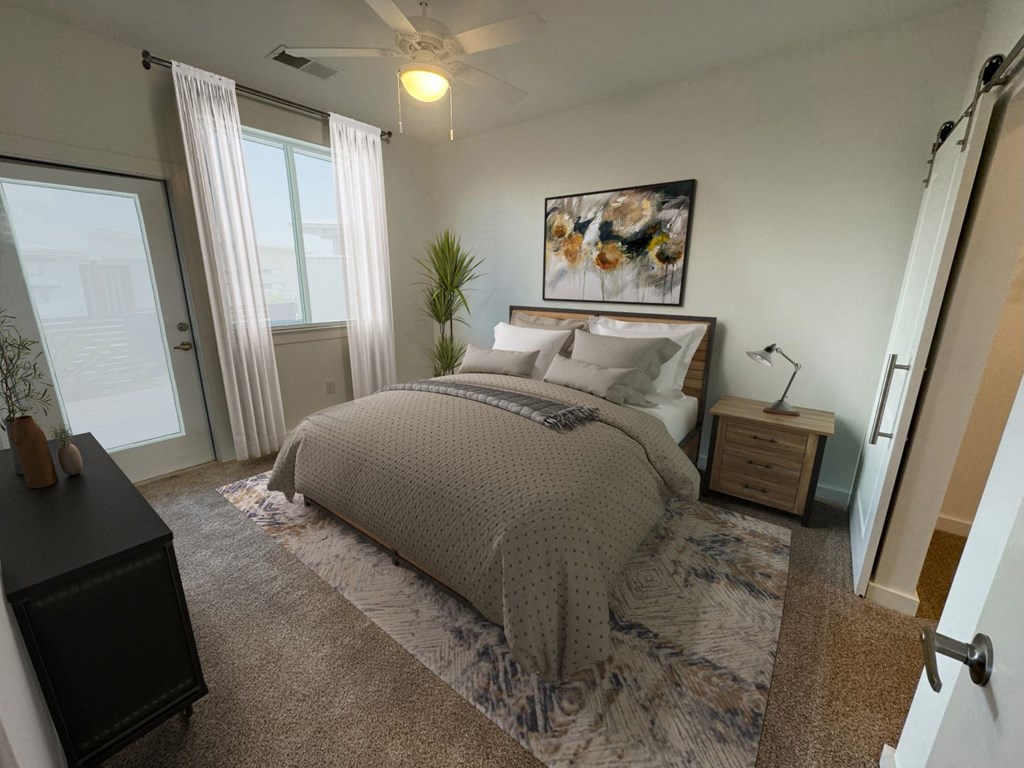 Apartments in Greenville SC with In-Unit Washer and Dryer - Alston - Bedroom with Plush Carpeting, Gray Bed, Bedside Table, Ceiling Fan, Window with White Curtains, and Door to Private Balcony
