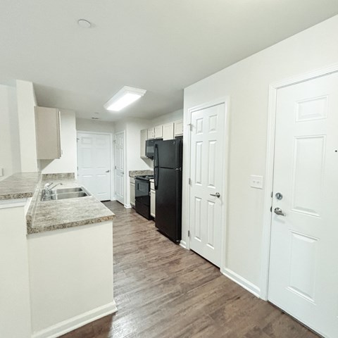 A kitchen with a black refrigerator and white cabinets.