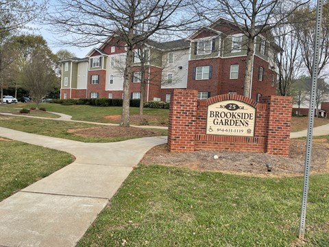 A brick sign that says Brookside Gardens in front of a building.