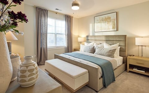 A bedroom with a large bed and a vase on the side table.