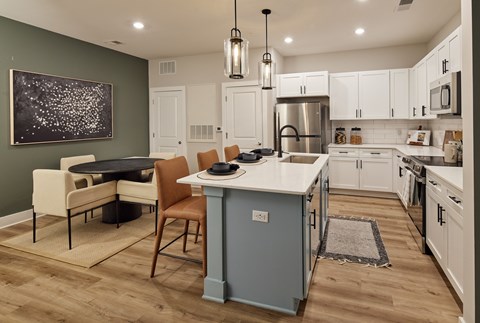 A kitchen with a table and chairs in front of a green wall.