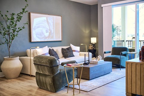 A living room with a white couch, a green chair, and a large painting on the wall.