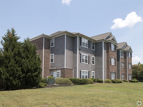 A large apartment building with a green bush in front.