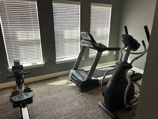 A room with exercise equipment and windows covered with blinds.