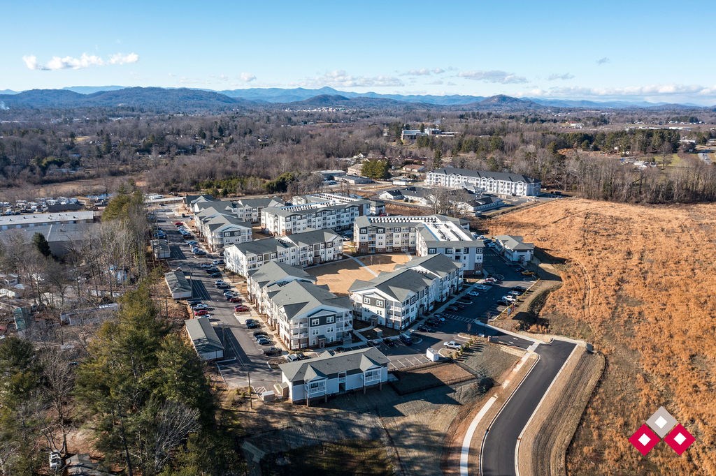 A large white building complex with a parking lot in front and a road curving around it.
