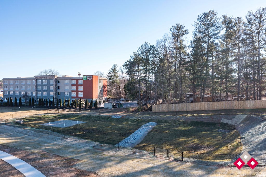 A park with a playground and a building in the background.