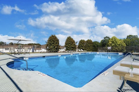 Reserve at Hillcrest Townhomes blue 3-4 foot pool with deck and chairs