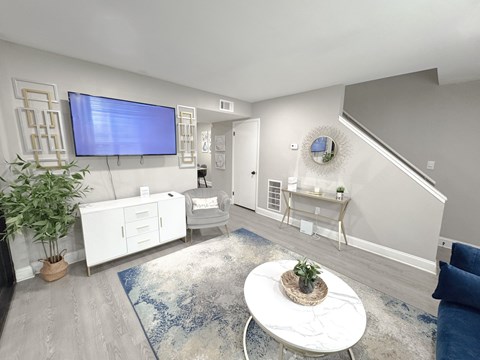 A living room with a white sofa and a television mounted on the wall.