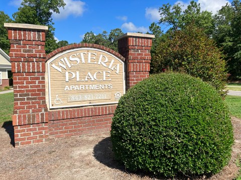 a brick sign for western place apartments in front of a bush